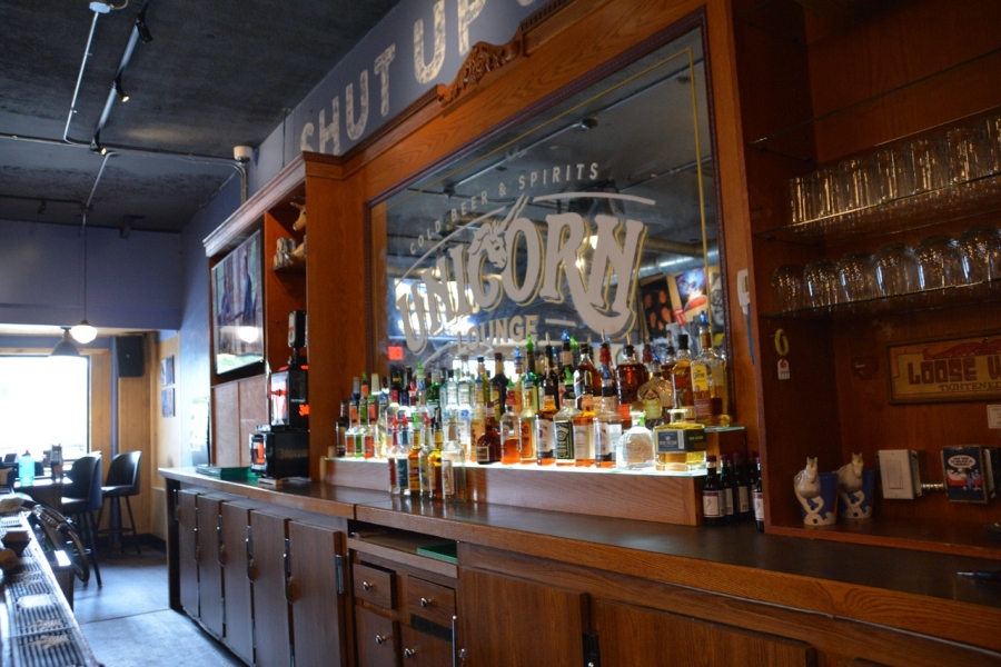Unicorn Lounge bar backdrop with liquor bottles and unicorn lounge logo painted on the glass